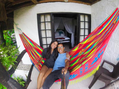 a man and a woman sitting in a hammock in a room at Hostal Villa Cata in El Zaino