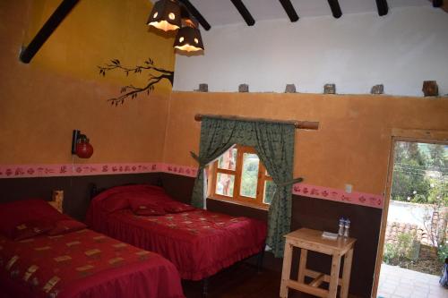 a room with two beds and a window in it at Hostal el castillo ingapirca in Ingapirca
