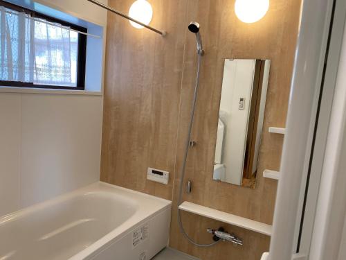uma casa de banho com uma banheira e um chuveiro com um espelho. em Platinum Yasaka em Quioto