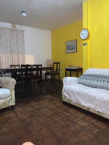 a room with two beds and a table and a clock at Casa na Enseada in Guarujá