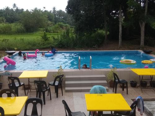 a pool with people in it with yellow tables and chairs at Captain's Cabin Resort - Naval Heritage (Swimming Pool) in Kota Bharu