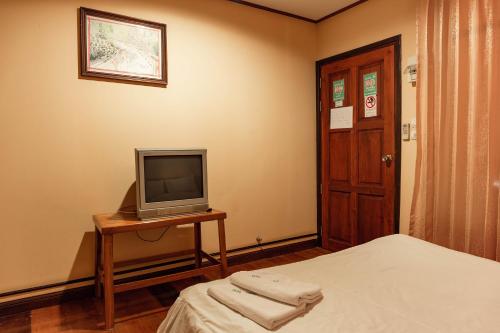 a room with a tv and a bed and a table at Baan Kitsada in Amphawa