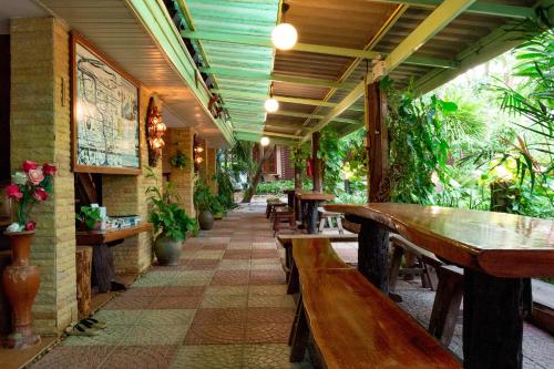 a restaurant with wooden tables and benches and plants at Baan Kitsada in Amphawa