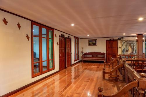 a living room with wooden floors and windows at Baan Kitsada in Amphawa