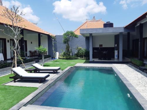 a swimming pool with two lounge chairs and a house at Plawa Bali Guest House in Canggu