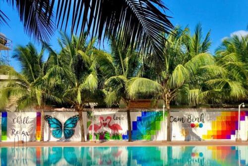 a colorful fence with palm trees and a butterfly on it at Cam Bình Resort in La Gi