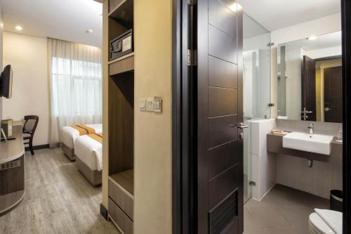 a bathroom with a sink and a toilet and a mirror at Oria Hotel Jakarta in Jakarta