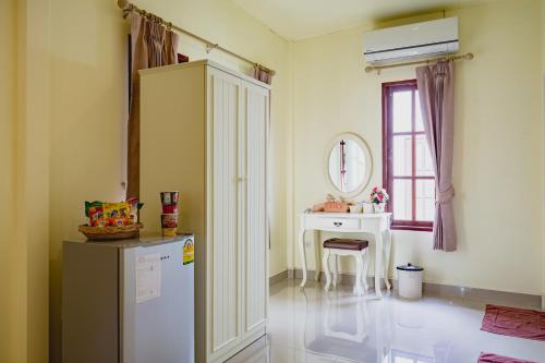 een keuken met een koelkast, een tafel en een raam bij Sakarin Valley Resort in Kanchanaburi