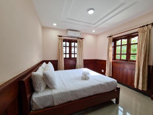 a bedroom with a bed and two windows at Con Dao Tan Son Nhat Hotel in Con Dao
