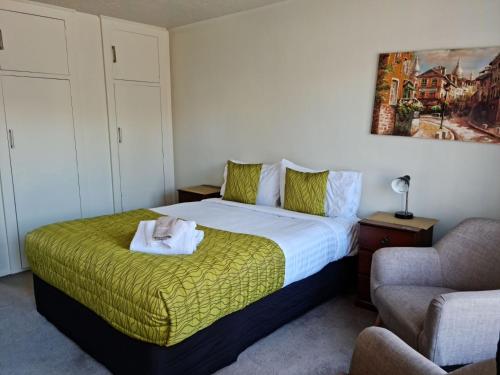 a bedroom with a bed with a towel on it at Cranford Cottages and Motel in Christchurch
