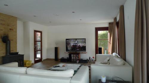 a living room with two white couches and a flat screen tv at Vakantiehuis - Rue du Château Deux in Voeren