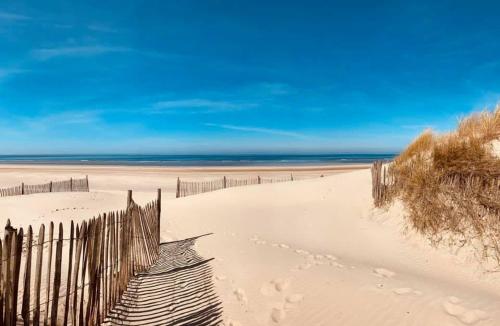 einen Zaun an einem Strand mit dem Ozean im Hintergrund in der Unterkunft La VILLA en BAIE in Le Crotoy