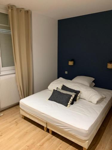 une chambre avec un lit blanc avec un mur bleu dans l'établissement Appartement charme avec terrasse, à Le Touquet-Paris-Plage