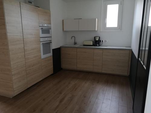 Il comprend une cuisine avec des placards en bois et du parquet. dans l'établissement Appartement charme avec terrasse, à Le Touquet-Paris-Plage