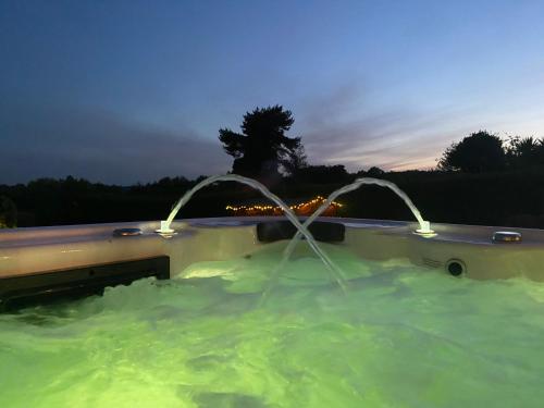 a pool of green water with fountains at Stunning guest suite with private hot tub in Rogerstone