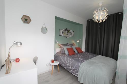 una camera da letto con un letto e un lampadario di L'Eden by EasyEscale a Romilly-sur-Seine