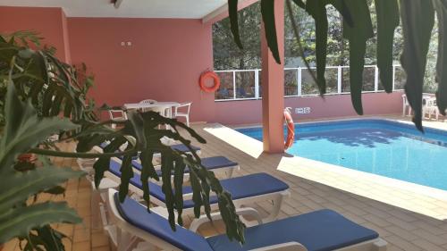 a resort pool with blue chairs and a plant at Boutique Hotel Marina S. Roque in Lagos