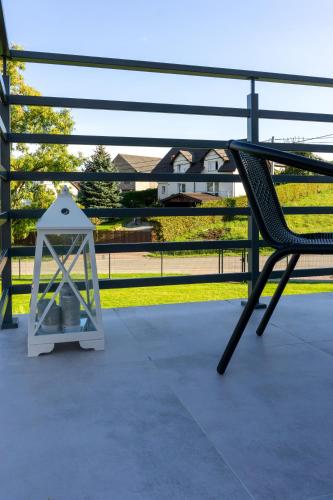 a porch with a chair and a clock on it at Trzy Małe Drzewka in Wielka Wieś