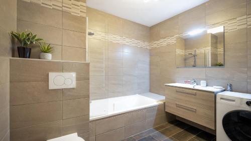 Les Freinets - Apt A01 - BO Immobilier في شاتيل: حمام مع حوض ومغسلة وحوض استحمام