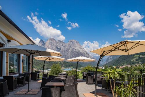 a patio with tables and chairs and umbrellas at Hotel Villa Imperina in Agordo