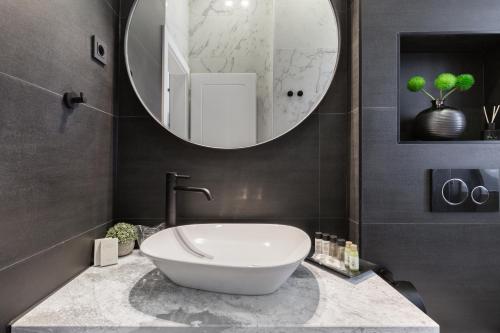 a bathroom with a sink and a large mirror at DeZign Superior Apartments & Rooms in Zadar