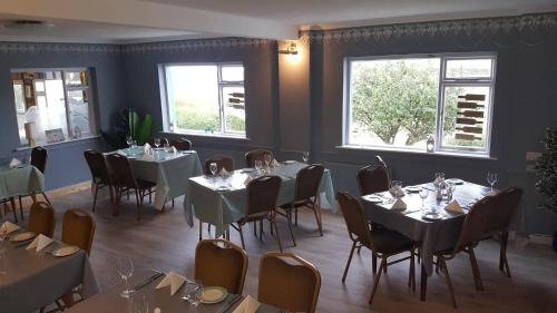 a dining room with tables and chairs and windows at O'Connors Guesthouse in Faha