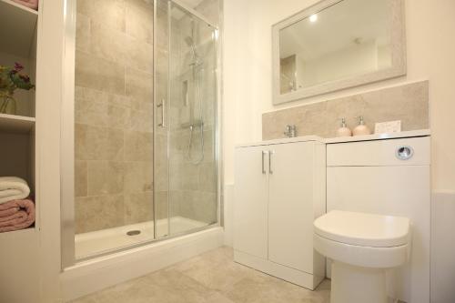 uma casa de banho branca com um chuveiro e um WC. em The Annexe in Ditcheat em Ditcheat