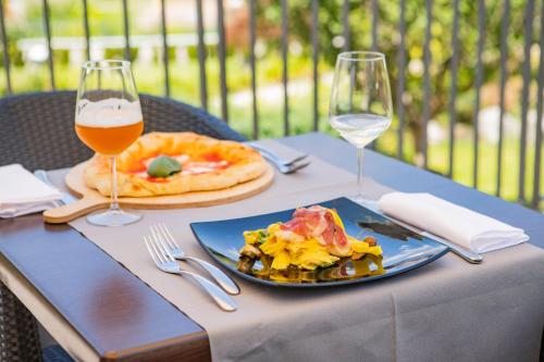 a table with a plate of food and two glasses of wine at Hotel Villa Imperina in Agordo