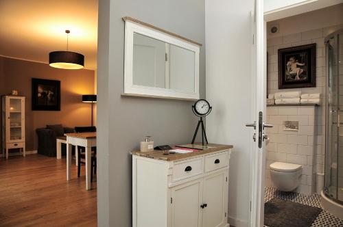 uma casa de banho com WC e um relógio no balcão em Apartamenty Kopernika 14 em Toruń