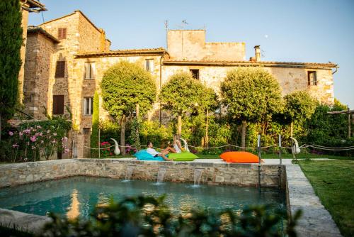two people sitting in a pool in front of a building at PALAZZO DEL CAPITANO Wellness & Relais - Luxury Borgo Capitano Collection in San Quirico dʼOrcia