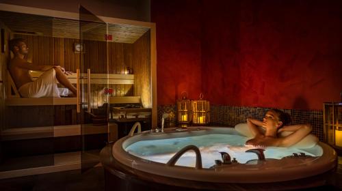 a man laying in a bath tub in a bathroom at Grand Hotel Adriatic in Opatija