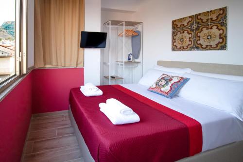 una camera d'albergo con un letto rosso e bianco con due asciugamani di Duca d'Aosta Terrace, Skypool & Sauna ad Acquedolci