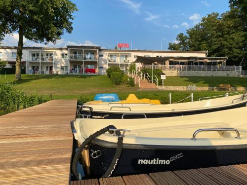 a boat sitting on a dock in front of a building at Hotel am Untersee in Bantikow