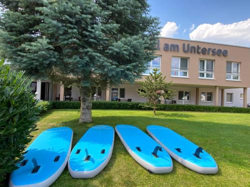 cztery niebieskie deski surfingowe siedzące w trawie przed budynkiem w obiekcie Hotel am Untersee w mieście Bantikow