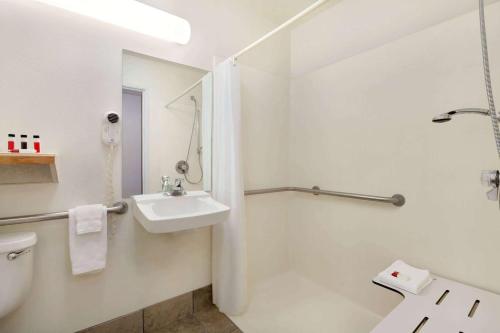 a white bathroom with a sink and a shower at Travelodge by Wyndham Yermo in Yermo