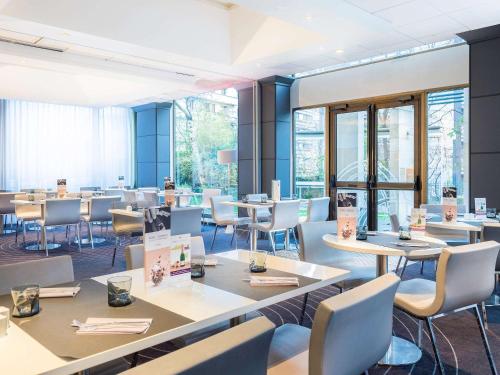 a restaurant with tables and chairs and windows at Mercure Paris Centre Tour Eiffel in Paris