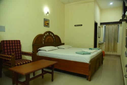 a bedroom with a bed and a table and a chair at Hotel Raja Palace in Kanyakumari