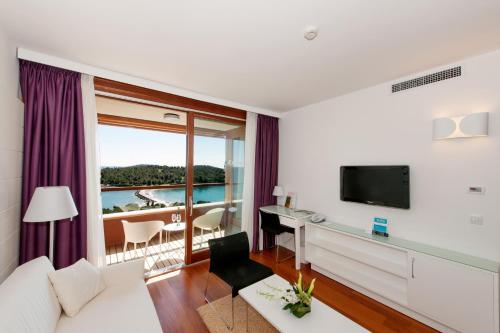 
a hotel room with a bed, table, television and window at All Suite Island Hotel Istra in Rovinj
