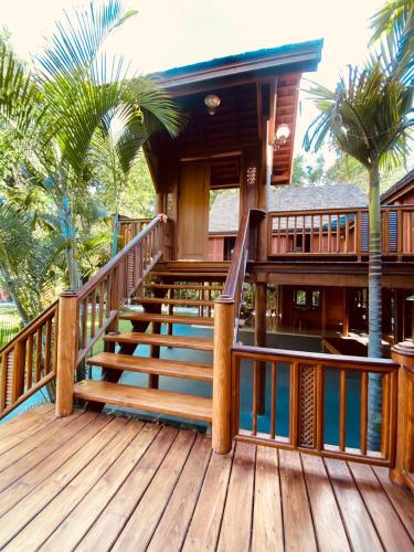 a house with a wooden deck with a staircase at SAK-KA-YA (สัก-กา-ยะ) in Mae Sot