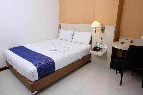 a bedroom with a bed and a telephone and a table at Rio City Hotel in Palembang