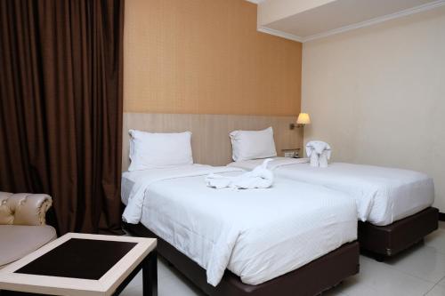 two beds in a hotel room with towels on them at Rio City Hotel in Palembang