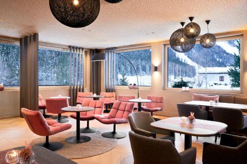 a restaurant with red chairs and tables and windows at Adler Inn Tyrol Mountain Resort SUPERIOR in Tux
