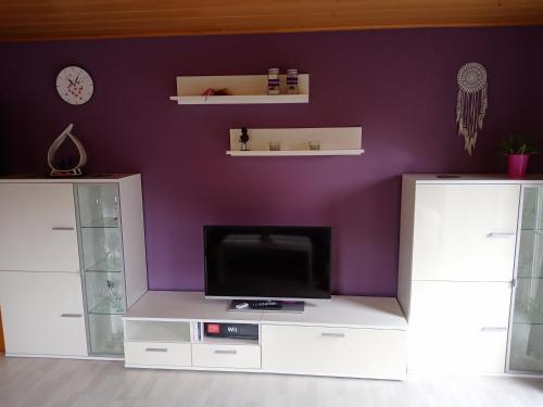 a living room with a tv and a purple wall at Ferienwohnung LAURA in Böbrach