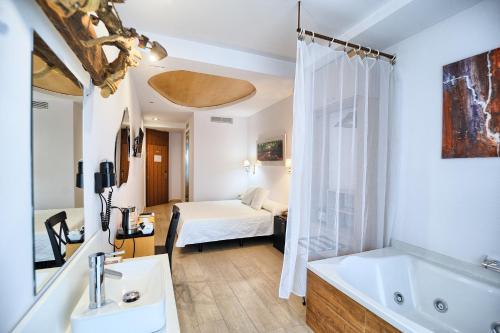 Hotel Sabbia by Gabbeach في فالنسيا: حمام مع حوض وسرير في الغرفة
