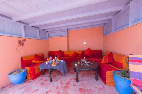 a room with red and orange couches and tables at Riad AYLAL in Essaouira