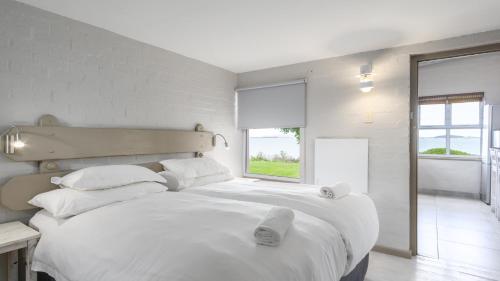 a white bedroom with a large bed with white sheets and pillows at Blue Bay Lodge in Saldanha