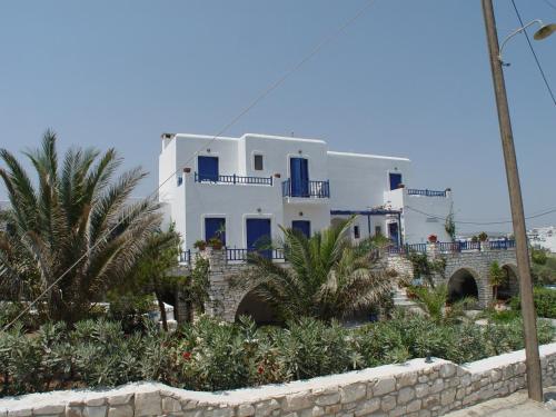 a white house with blue windows and a fence at Ragoussis House in Logaras