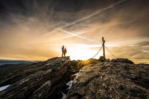 a man standing on top of a mountain at sunset at Adler Inn Tyrol Mountain Resort SUPERIOR in Tux