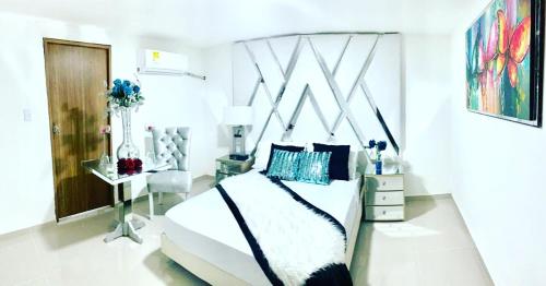 a bedroom with a large white bed and a table at Hotel Platinum Barranquilla in Barranquilla