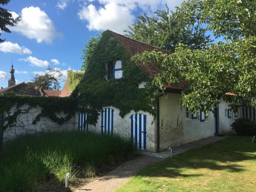 an old brick house with ivy growing on it at Authentic wellnesshoeve in Hansbeke